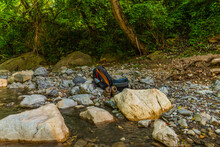 A Backpack, Camera Bag And Hiking Boots On A Riverbank Of A Mountain River During A Hiker's Break