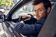 © Roman - Confident young man in full suit and eyewear looking back while parking his car