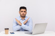 © khosrork - This is the end, finish! Strict boss sitting office workplace with laptop on desk, crossing hands showing x sign stop gesture, warning of troubles. indoor studio shot isolated on white background