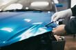 © hedgehog94 - Car wrapping specialist putting vinyl foil or film on car. Selective focus.