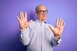 © Krakenimages.com - Middle age handsome hoary man wearing striped shirt and glasses over purple background afraid and terrified with fear expression stop gesture with hands, shouting in shock. Panic concept.