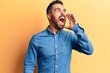 © Krakenimages.com - Young hispanic man wearing casual clothes shouting and screaming loud to side with hand on mouth. communication concept.