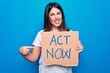 © Krakenimages.com - Young beautiful brunette woman asking for reaction holding banner with act now message smiling happy pointing with hand and finger