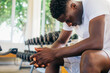 © twinsterphoto - Desperate African American male athlete sitting on bench during break in fitness training in modern gym