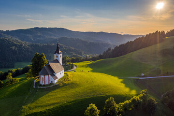 Sveti Andrej, Slovenia - Aerial drone view of Saint Andrew church (Sv. Andrej) at sunset in Skofja Loka area. Summer time in the Slovenian alps