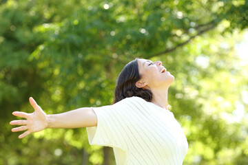 Happy adult woman breathing fresh air in the park