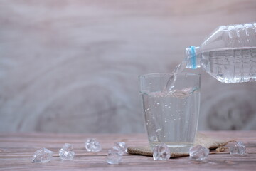 Sticker - Pouring drinking water on wooden table background and space for text 