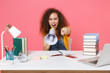 Canvas Print - Angry african american girl employee in office isolated on pink background. Achievement business career. Education in school university college concept. Screaming in megaphone, point finger on camera.