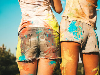 Two girls making party at Holi colors festival in summer time.Young women friends having fun after music event at sunset. Cheerful models smeared with colored paints in the park