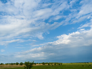 Blue sky and clouds over green fields. Summer sunny day