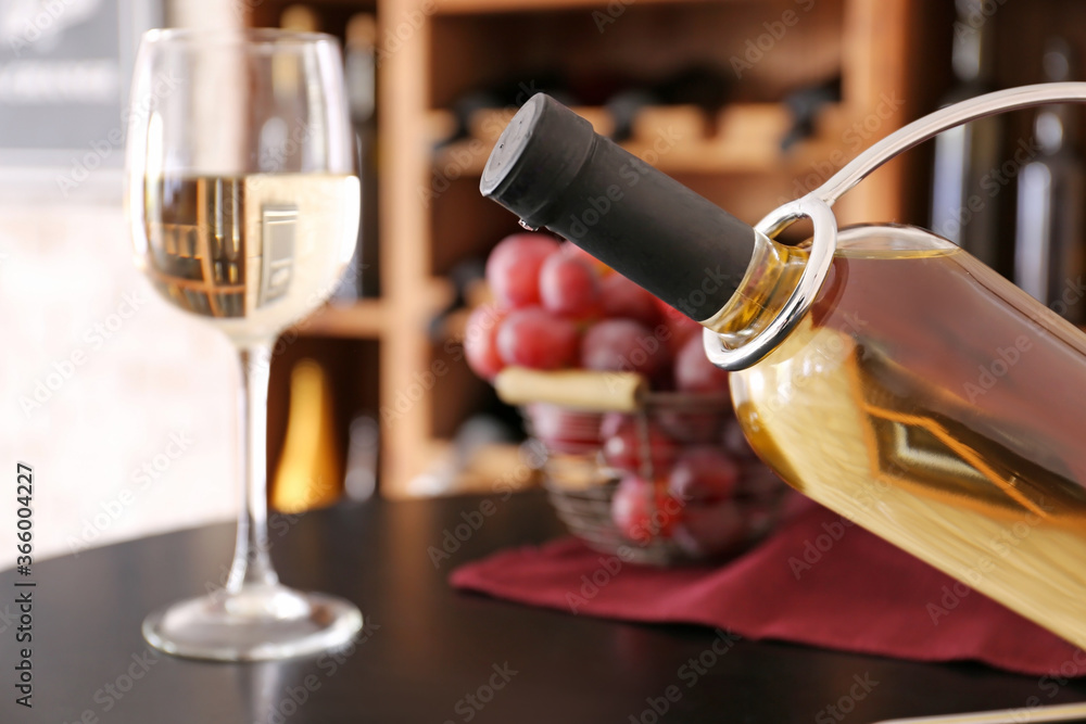 Holder with bottle of wine on table in cellar, closeup
