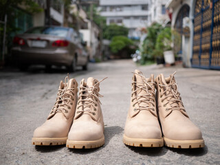 Front view of male and female boots are placed in the middle of the road in front of the house