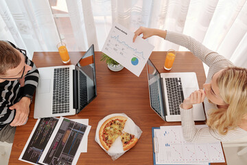 Wall Mural - young woman showing visitors activity chart to her husband programmer when they are working on new m