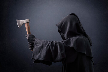 Wall Mural - Scary figure in hooded cloak with axe in the dark