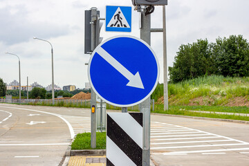 Blue and white warning round turn direction indication road sign with an arrow for cars.