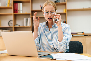 Canvas Print - Image of businesswoman talking on cellphone while working with laptop