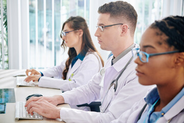 Concentrated young laboratory workers entering results of research in computers