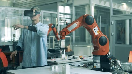 Male developer in VR-glasses is working with high-tech robot