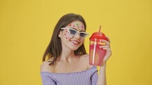 A Smiling Stylish Young Girl With Fashion Makeup And Stickers On The Face Is Holding A Red Drink In A Cup Standing Isolated Over A Yellow Background