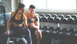 © NVB Stocker - Personal fitness trainer assisting attractive woman with workout at gym health club. Young Woman lifting dumbbell with male trainer. Fitness Healthy lifestye and workout at gym concept.