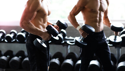 Young Man Naked bodybuilder exercising lifting with dumbbell at gym. .Gym equipment and sport concept. Fitness Healthy lifestye and workout at gym concept.