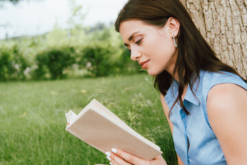 beautiful young woman reading book outside