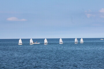 Civitavecchia,Italy -July 18,2020 : Sailboat instruction,The row of sailboat students are practice sailing near the A seaport on the Tyrrhenian Sea.Also have guideline and guarding boat,italy summer