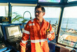 © Igor Kardasov - Filipino deck Officer on bridge of vessel or ship wearing coverall during navigaton watch at sea . He is speaking on portable GMDSS VHF radio, short range communication