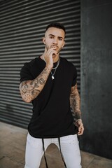 Wall Mural - European tattooed hip male in a black shirt and white ripped jeans, and metal chain