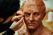 © Cavan Images - Close up of sculptor finishing a clay head eye in an art studio