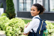 © LIGHTFIELD STUDIOS - side view of smiling african american schoolgirl with book outdoors