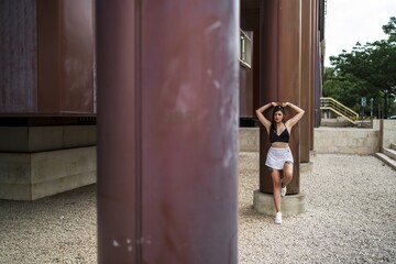 Canvas Print - Young caucasian female posing while leaning on a column of a building