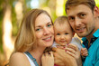 © Sk Elena - Happy family spent time together outdoors. Portrait of mother, father and baby looking at camera. Summer time.