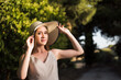Young woman enjoying the summer sun. Beautiful blonde girl with hat looks at camera 