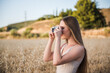 Caucasian blonde girl taking picture in the field. Young girl enjoys holidays with her camera