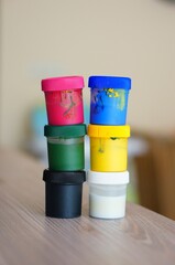 Vertical selective focus shot of two colorful paint container stacks on a table