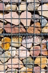 Sticker - Vertical closeup shot of colorful rocks behind a gray metal fence