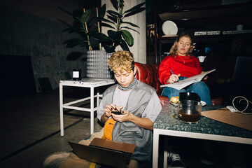 Male entrepreneur using smart phone while female coworker working in creative office