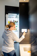 © Maskot - Woman using digital tablet on smart refrigerator at modern home