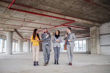 Wall Mural - Two muslim investors walking around building in construction process and talking with real estate agents about investment.