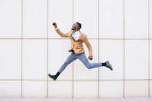 Young Businessman Jumping And Taking A Selfie In Front Of A Wall