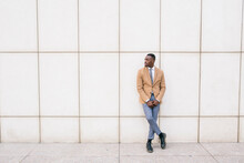 Young Businessman Leaning Against A Wall Looking Sideways