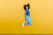 © VISTA by Westend61 - Pretty woman jumping for joy in front of yellow wall
