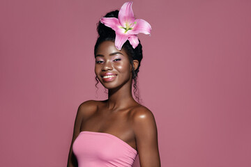 Wall Mural - pink lily hair style. young beautiful african american model with bunned hair smiling and posing aga