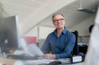 © Westend61 - Smiling mature male entrepreneur looking away while sitting with document