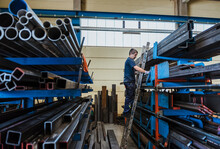 Man Working With Metal Bars On A Shelf In A Factory