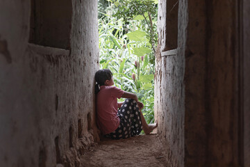 Sad and depressed young girl sitting alone looking outdoor