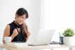 © NT_studio - Beautiful portrait asian young woman smile working online laptop computer with happy satisfied sitting on desk office, girl using notebook with excited and glad, business and success concept.