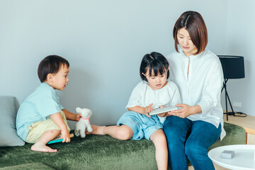 Wall Mural - 白くて明るいリビングで親子が本を読んでいる　family book
