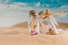 View Of The Sandy Beach And Shells In Two Glass Jar On Sand And Summer Beach
